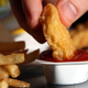Person dunking McNugget into ketchup